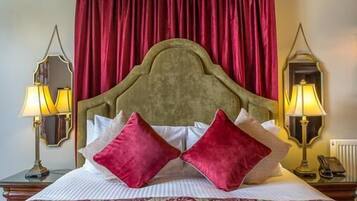 Quarto com cama grande, cortinas vermelhas e duas luminárias fixadas na parede.