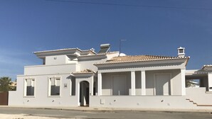 Un edificio de dos pisos con techo de tejas, una antena parabólica y una estructura pequeña similar a una torre en el techo.