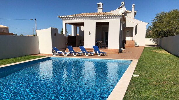Una piscina rectangular con agua cristalina y azul, rodeada por un césped bien cuidado.