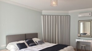 Un dormitorio ordenado con cama, mesita de noche y espejo sobre un tocador.