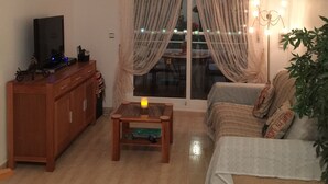 Un salon avec un téléviseur, un meuble en bois et un canapé.