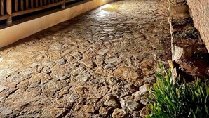 Un chemin de pierre menant à un bâtiment doté d’une balustrade en bois, avec une vue sur la mer la nuit.