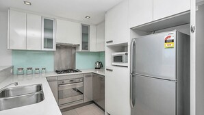 Eine moderne Küche mit Edelstahlgeräten, weißen Schränken und einer gefliesten Spritzschutzwand.
