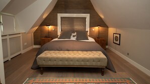 Une chambre à coucher avec un grand lit, une tête de lit en bois et un plafond en pente.