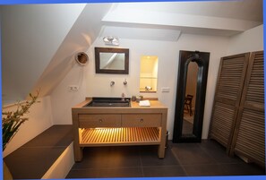 A modern bathroom with a wooden vanity, a large mirror, and a skylight. - Beautiful cottage in Laren (Laren)
