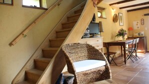 A staircase with wooden steps and a wicker chair at the bottom. - Une Sorcière sur le toit - Gîte** en Aveyron: Countryside and absolute tranquillity! (Firmi)