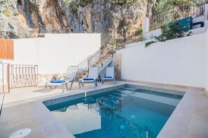 Relax by the clear pool surrounded by a deck and stairs leading to an upper level.