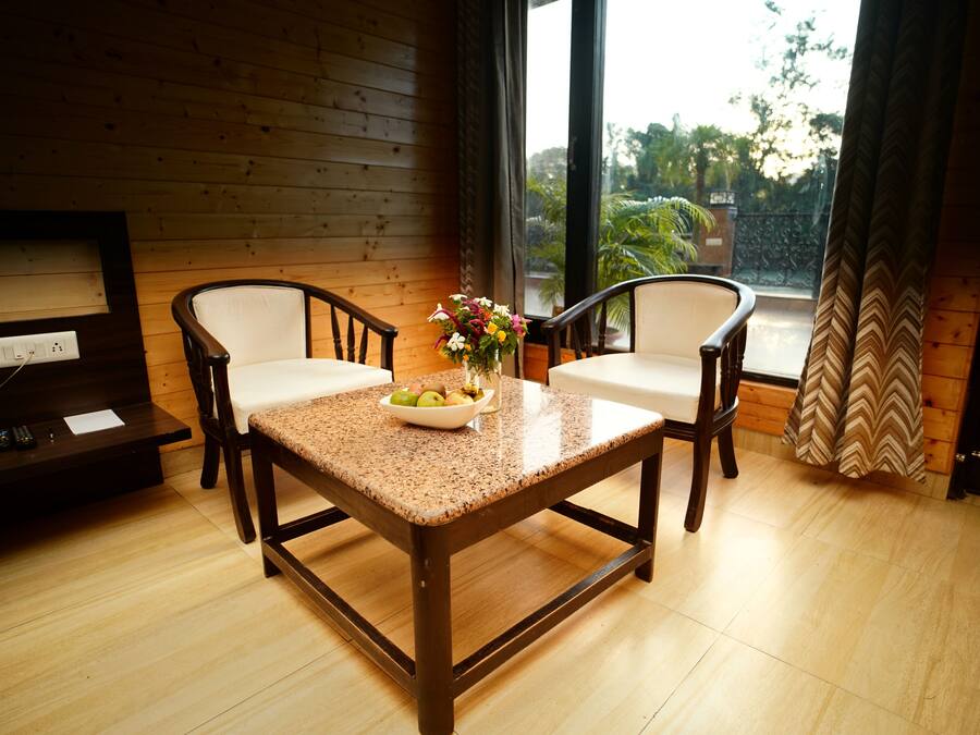 A wooden-paneled room with a table and two chairs, a vase with flowers, and a view of greenery outside.