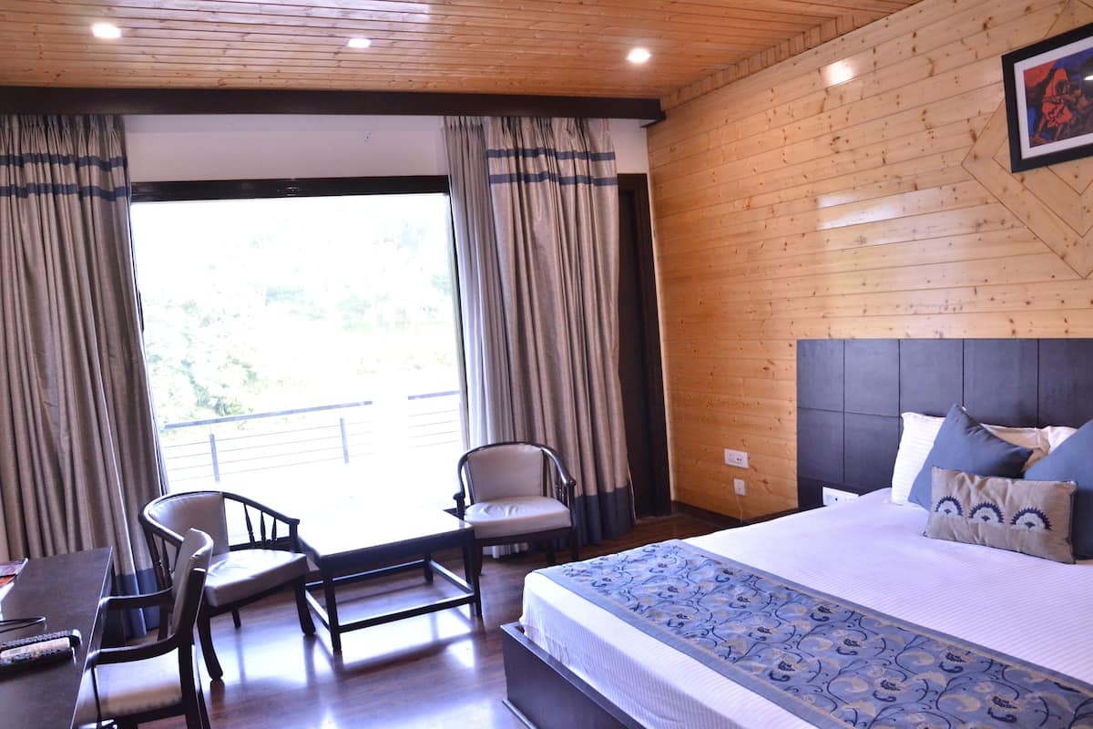Habitación de hotel con una cama, dos sillas, una mesa y vistas al exterior.