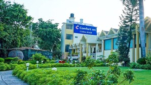 A Comfort Inn Coral River hotel with a well-maintained garden and a clear pathway leading to the entrance. - Comfort Inn Coral River (Pathankot)