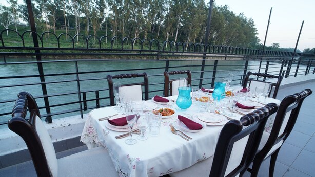 A table set for dining with a view of a river and greenery in the background. - Comfort Inn Coral River (Pathankot)