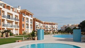 Un complexe hôtelier doté d’une piscine centrale, de nombreux balcons et d’un espace pelouse bien entretenu.