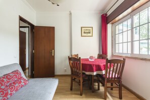 A dining area with a wooden table, red tablecloth, and wooden chairs.
