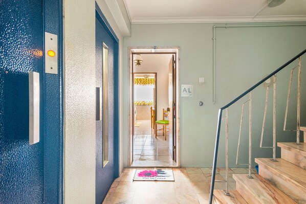 A hallway with a blue door, a staircase, and a mat with the text 'Mon tapis nature' on the floor.