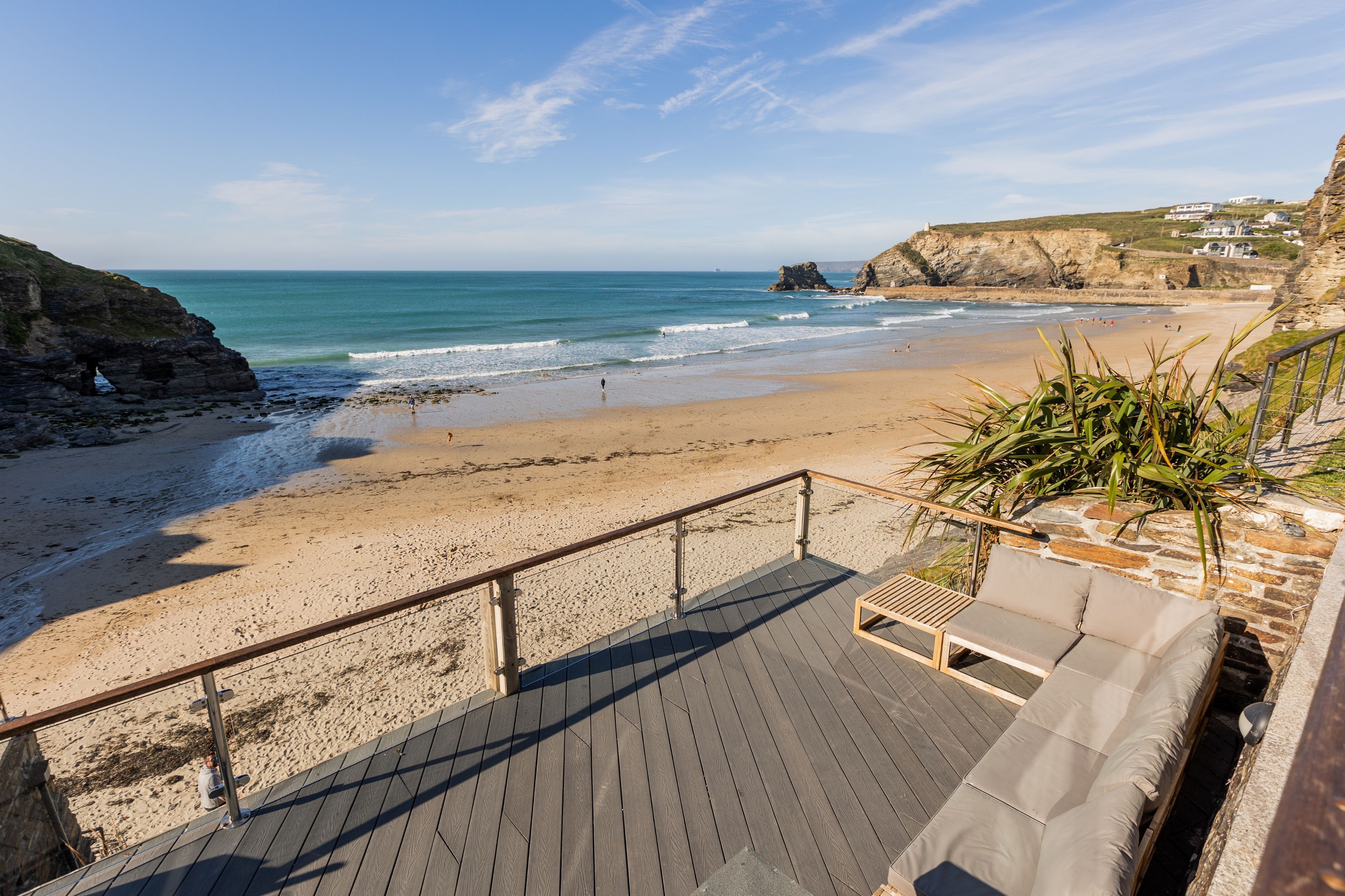 A beach with a wooden deck and a lounge area with cushions.