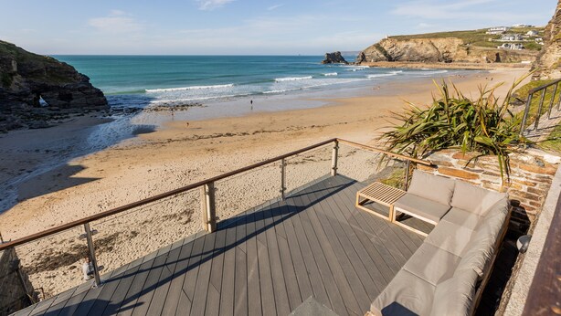 Une plage avec une terrasse en bois et un espace détente doté de coussins.