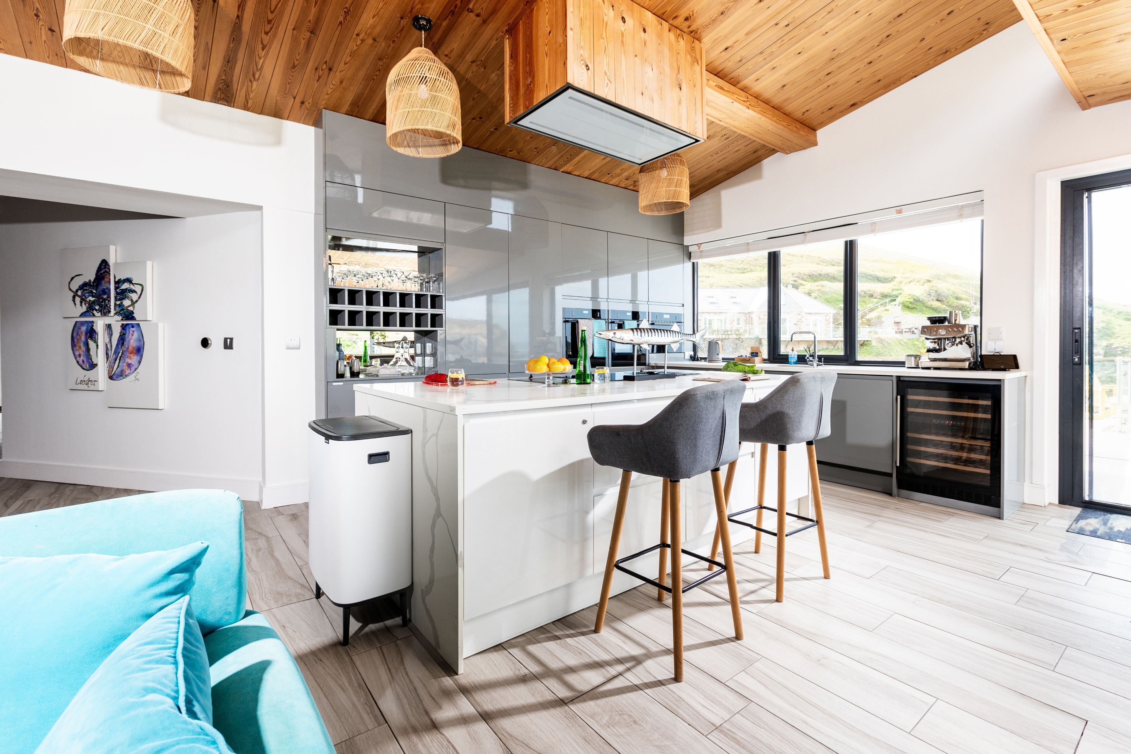 Una cocina moderna con una isla central, taburetes de bar y vistas al campo.