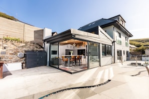 Una casa moderna con un patio in vetro, un muro in pietra e un'area pranzo.