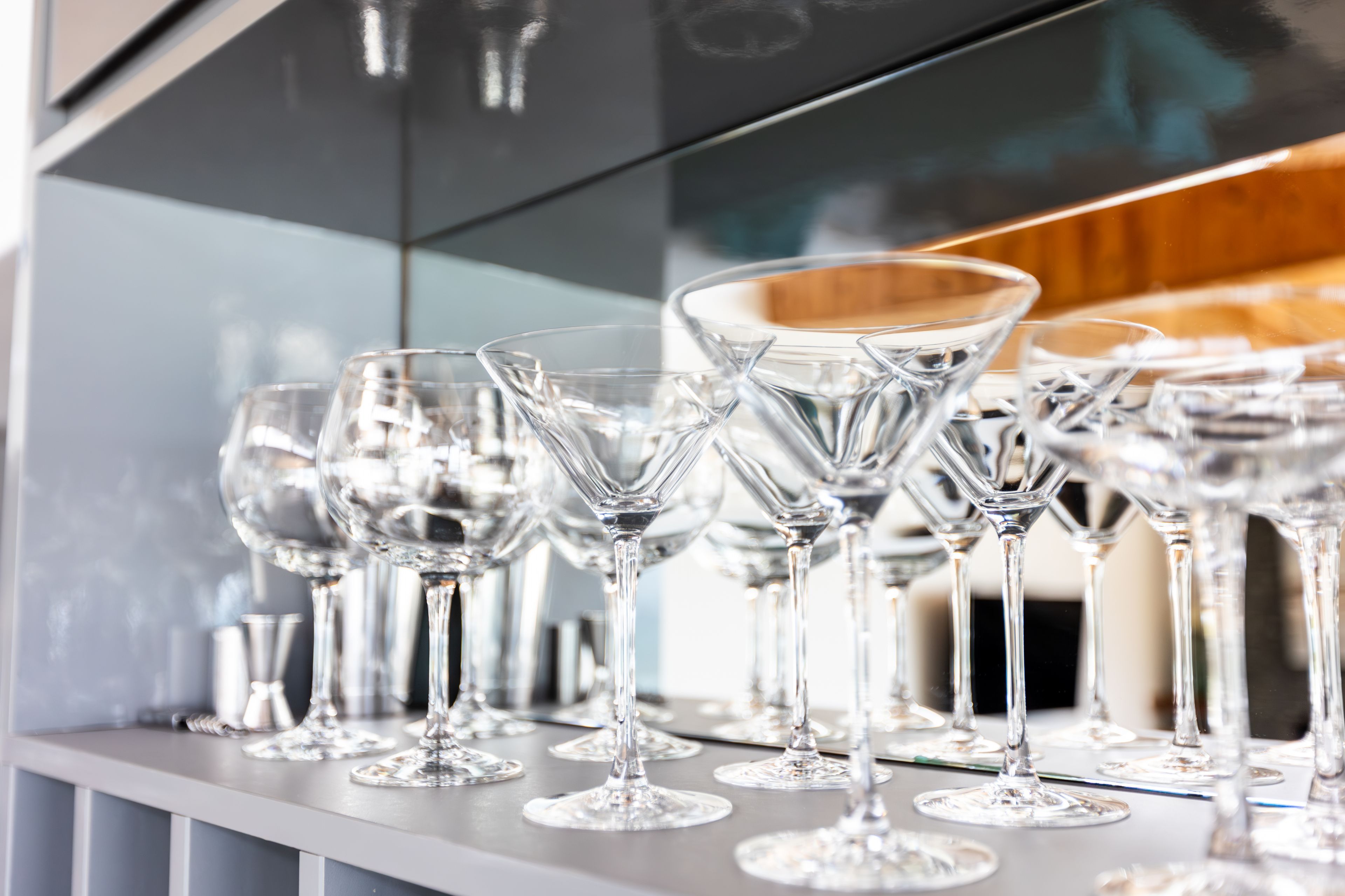 A row of empty wine glasses on a reflective surface.
