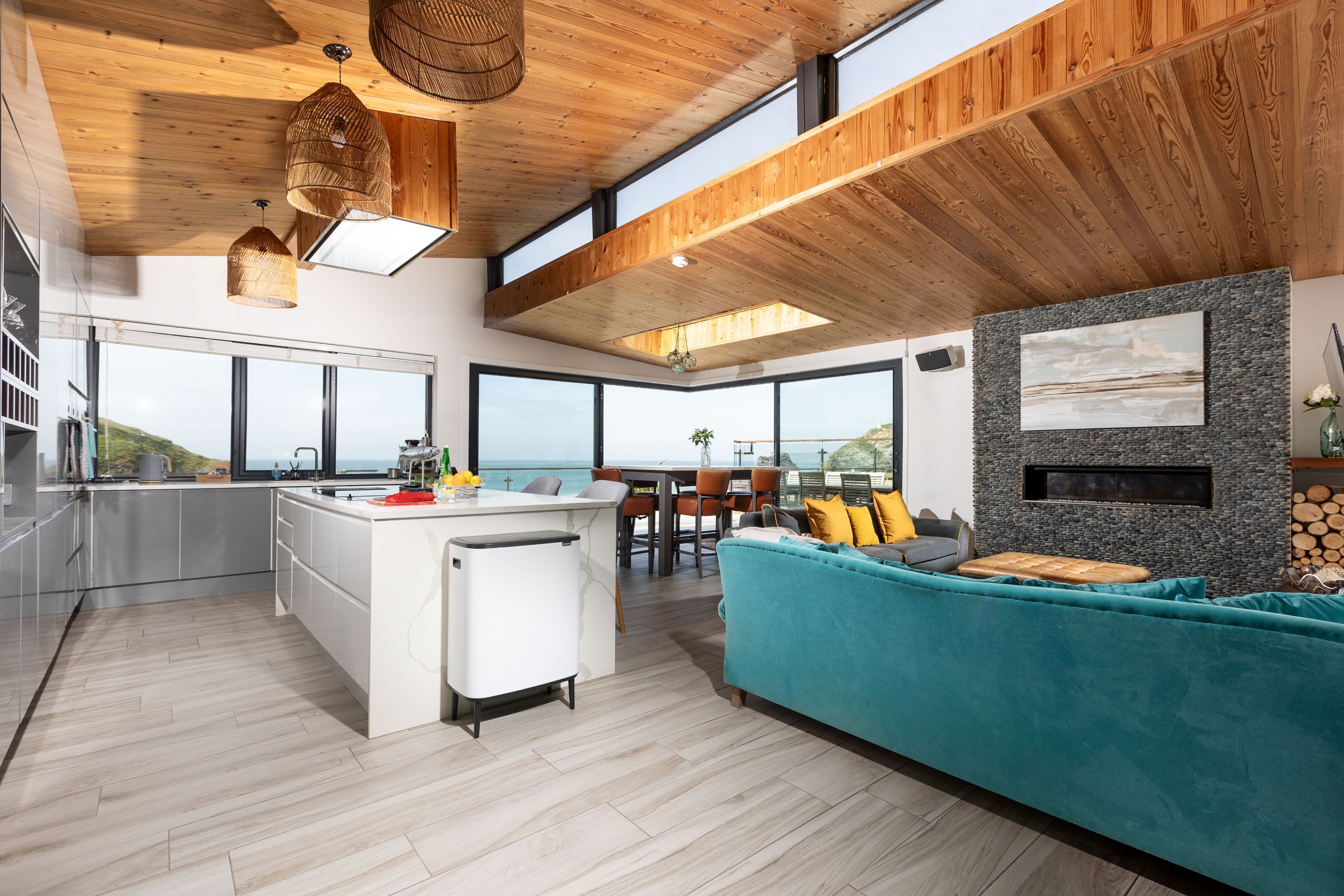 A modern kitchen with a large island, a dining area with a view, and a cozy seating area with a fireplace.