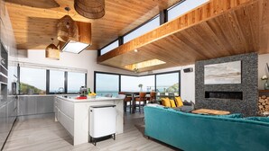 A modern kitchen with a large island, a dining area with a view, and a cozy seating area with a fireplace.