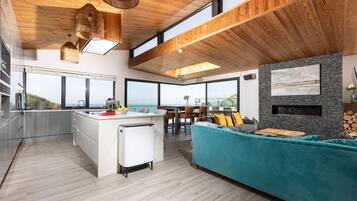 A modern kitchen with a large island, a dining area with a view, and a cozy seating area with a fireplace.