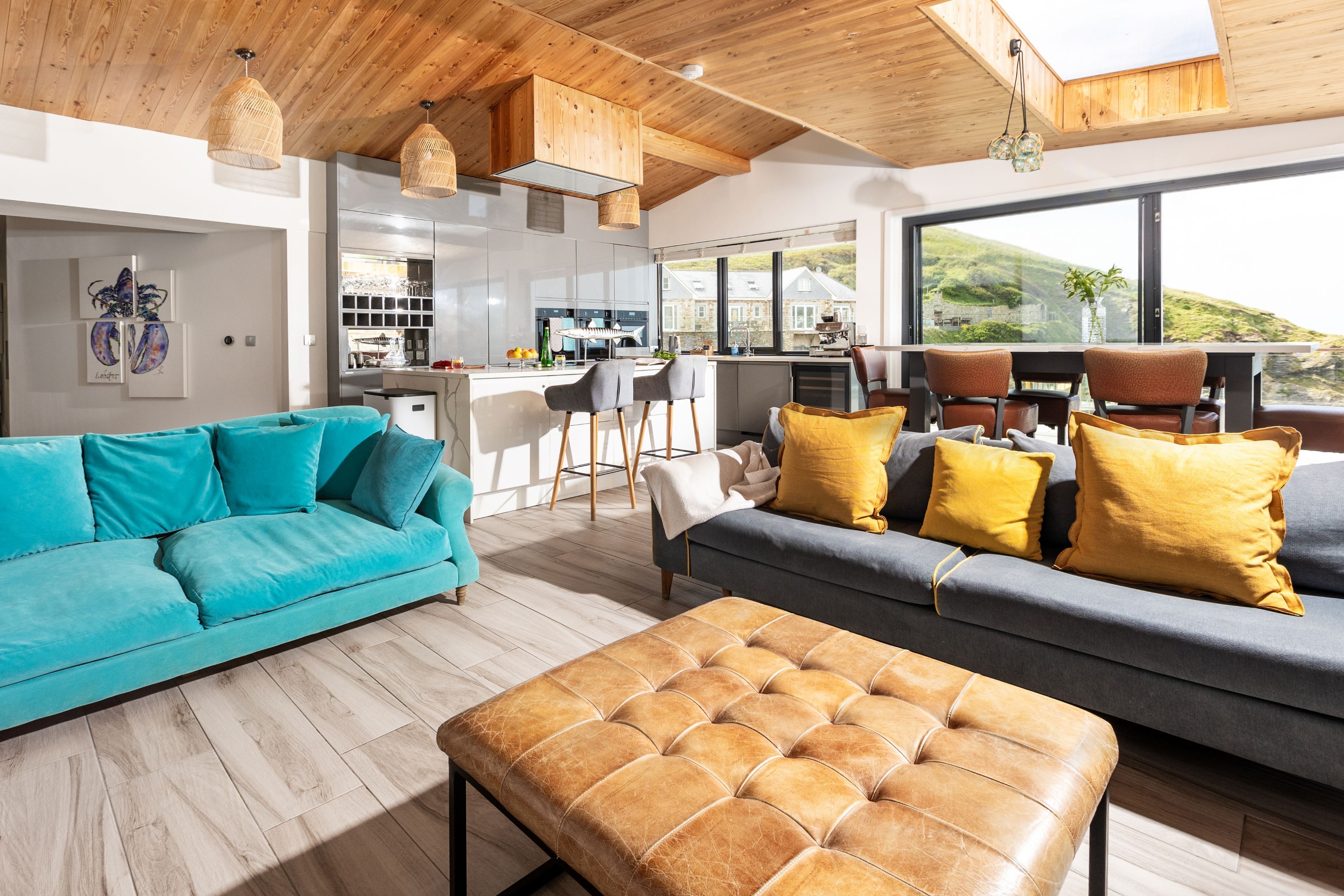 Un salon moderne avec un canapé, un pouf et un coin repas.