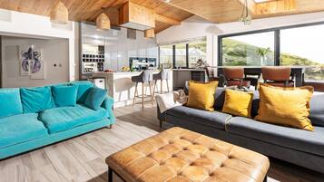 A modern living room with a sofa, ottoman, and dining area.