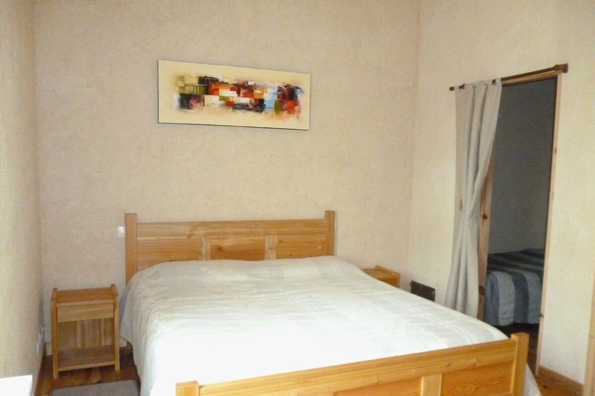 Un dormitorio con una cama de madera, una mesita de noche y una puerta con cortina.
