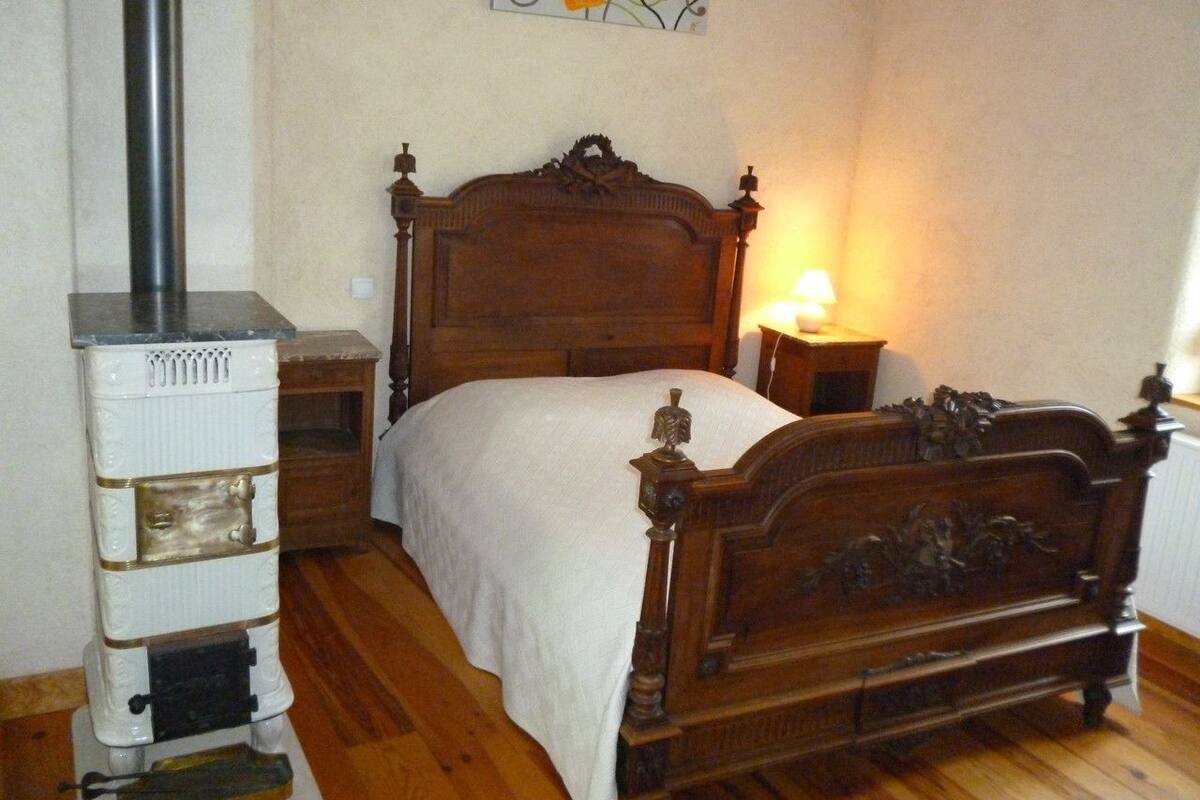 Un dormitorio con una cama de madera, un calentador blanco y una pequeña mesita de noche con lámpara.