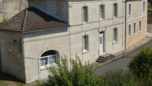 A two-story stone building with a tiled roof, arched windows, and a small entrance with steps. - Chambres d'hôtes Le Bourdieu (Soulignac)