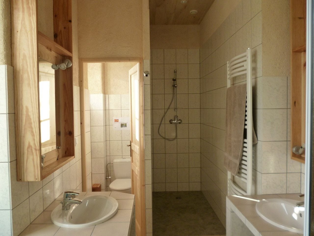 A bathroom with two sinks, a shower, and a toilet.