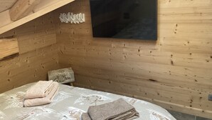 Een houten kamer met een bed, een wandtelevisie en een decoratief wandobject.