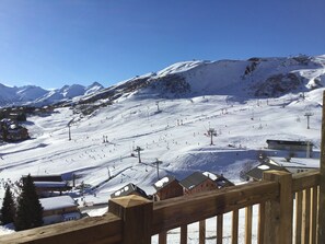 Une piste de ski enneigée, avec des remontées mécaniques et des bâtiments en arrière-plan.