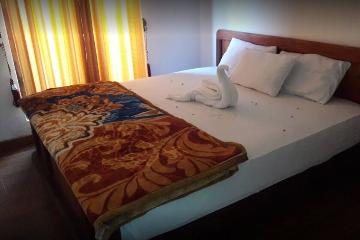 Een hotelkamer met een bed, een decoratieve spreidek en een handdoek in de vorm van een zwaan.