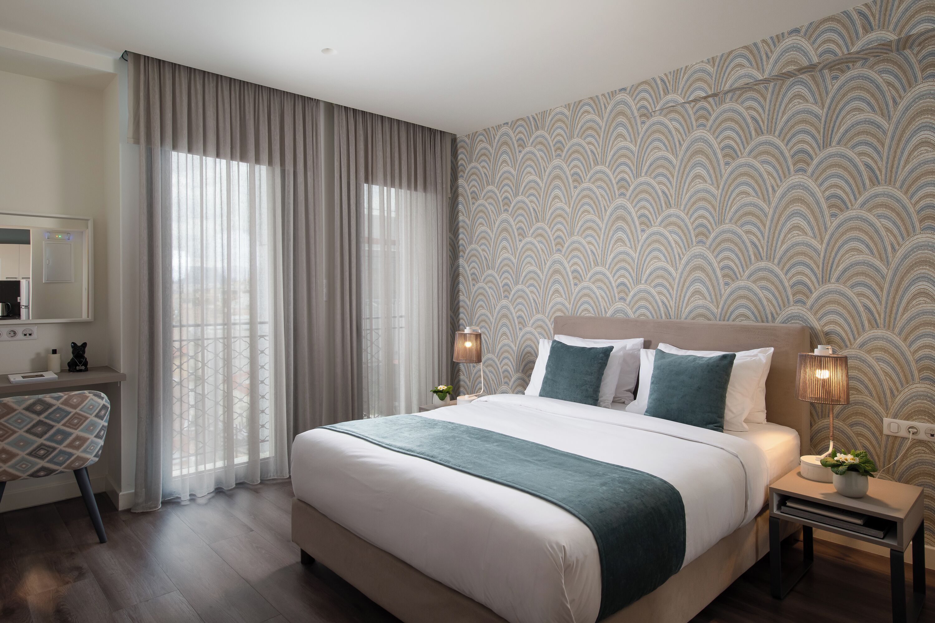 A modern hotel room with a large bed, a desk, and a chair.