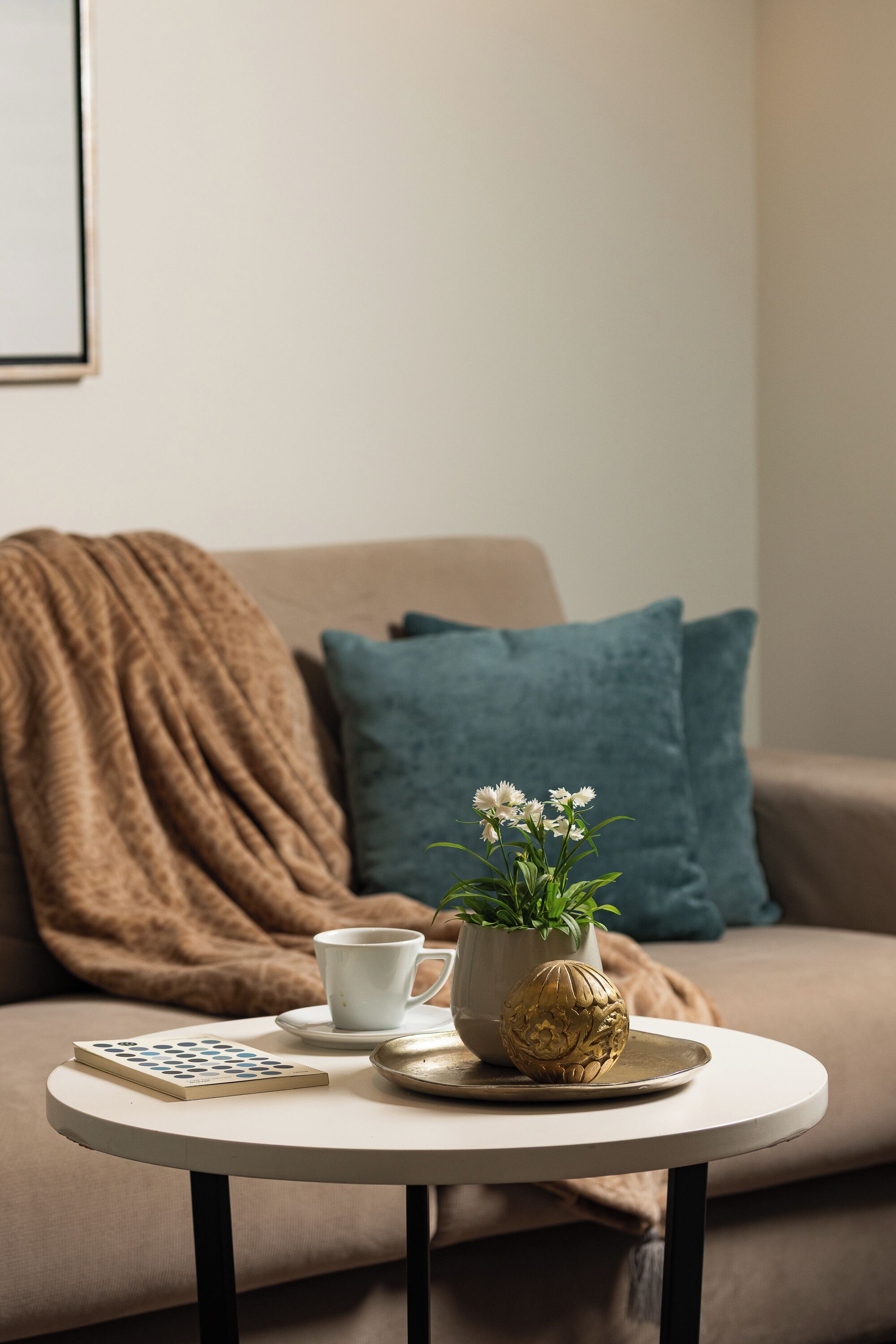 A round table with a white mug, a small potted plant, and a decorative item.