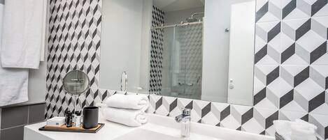 Een moderne badkamer met een grote spiegel, een wit wastafelmeubel en een douche.