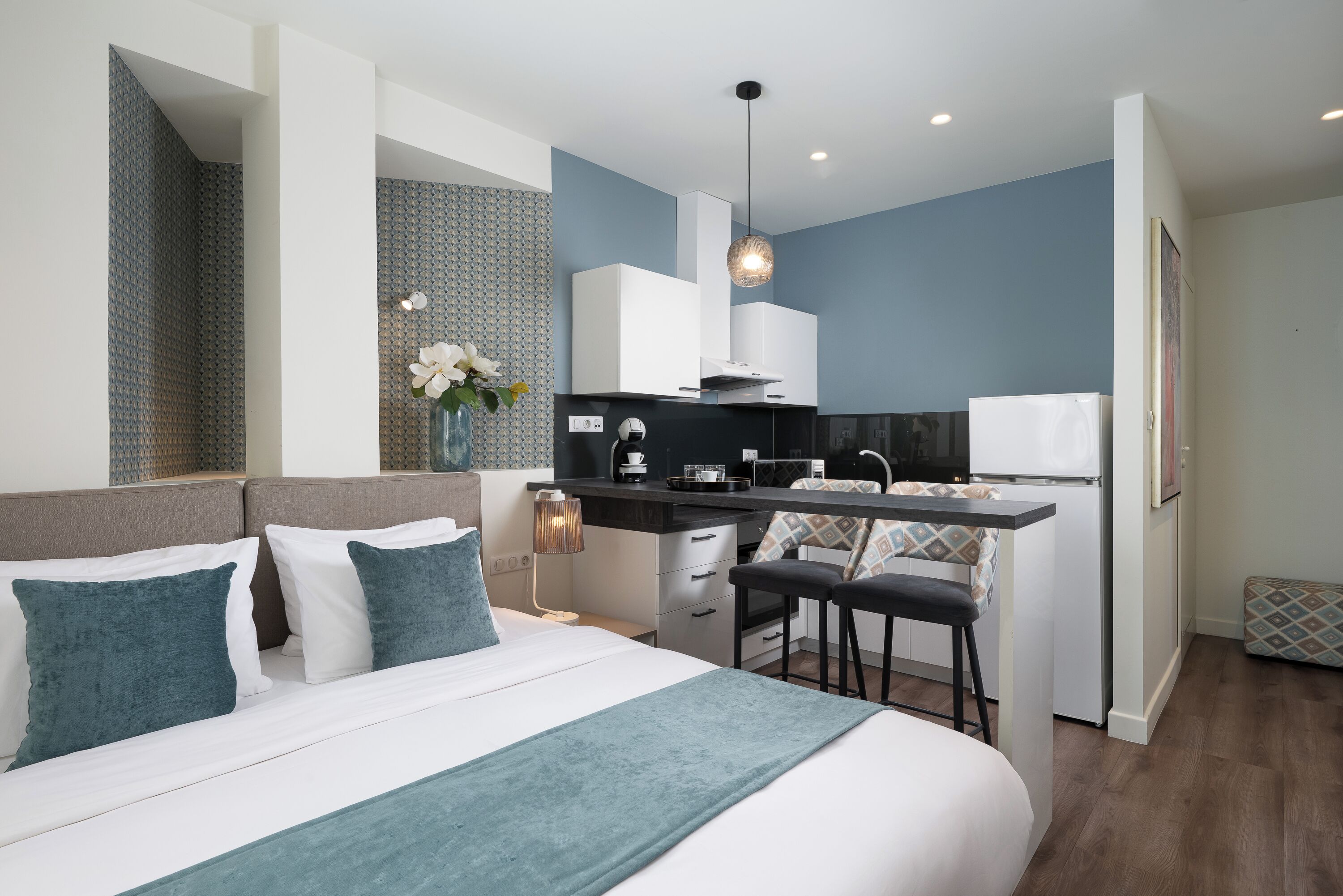 Una habitación de hotel moderna con una cama, kitchenette y un pequeño comedor.