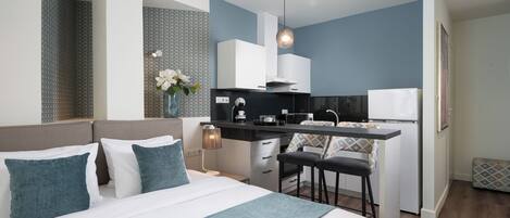 Una habitación de hotel moderna con una cama, kitchenette y un pequeño comedor.