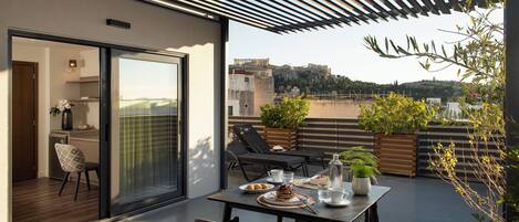 A modern outdoor dining area with a table set for two, a chair, and a view of a cityscape.