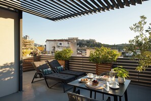A rooftop terrace with a dining table, lounge chairs, and potted plants. - Urban Nest - Suites & Apartments (Athens)