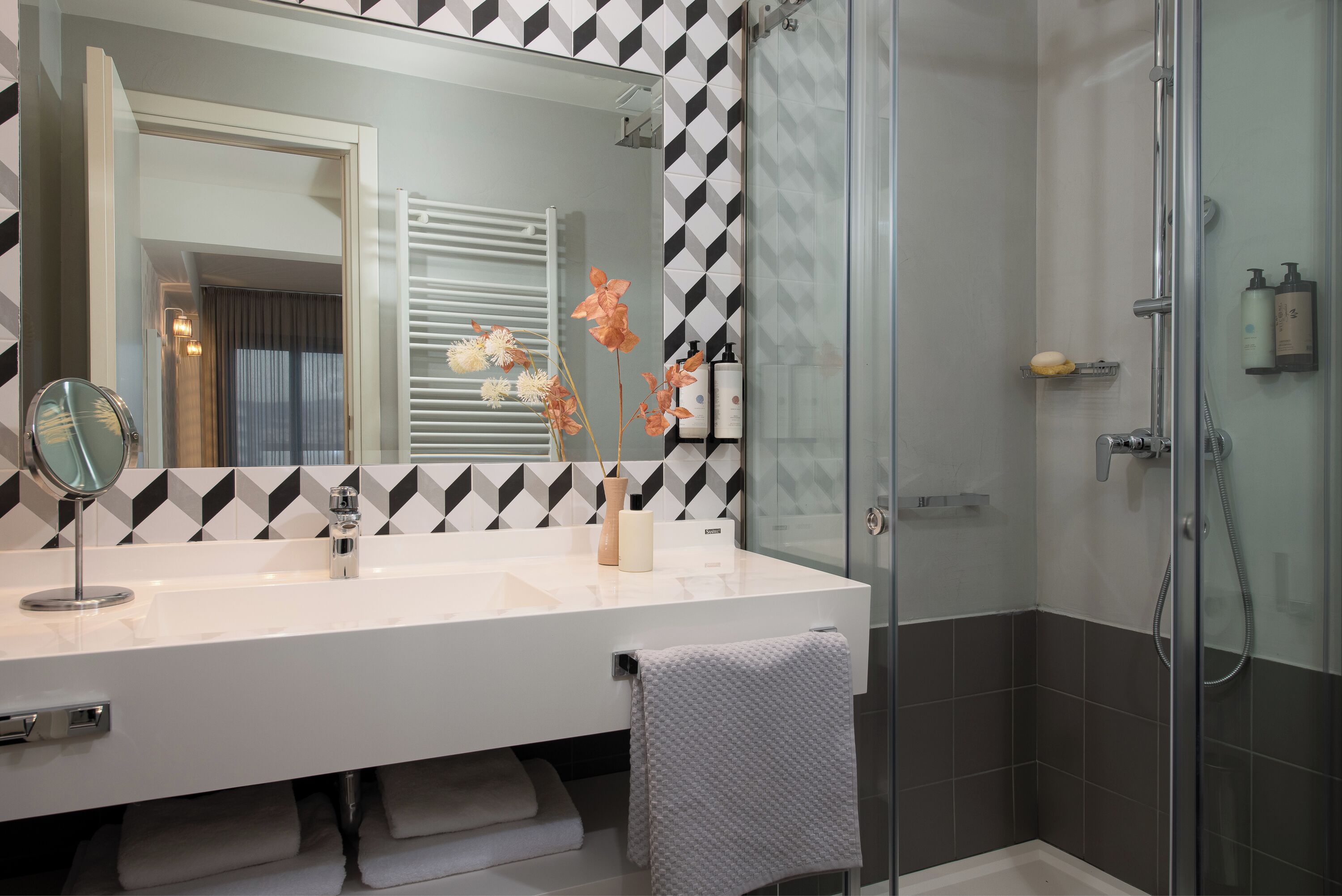 A modern bathroom with a white vanity, a large mirror, and a glass shower enclosure.