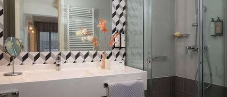 A modern bathroom with a white vanity, a large mirror, and a glass shower enclosure.