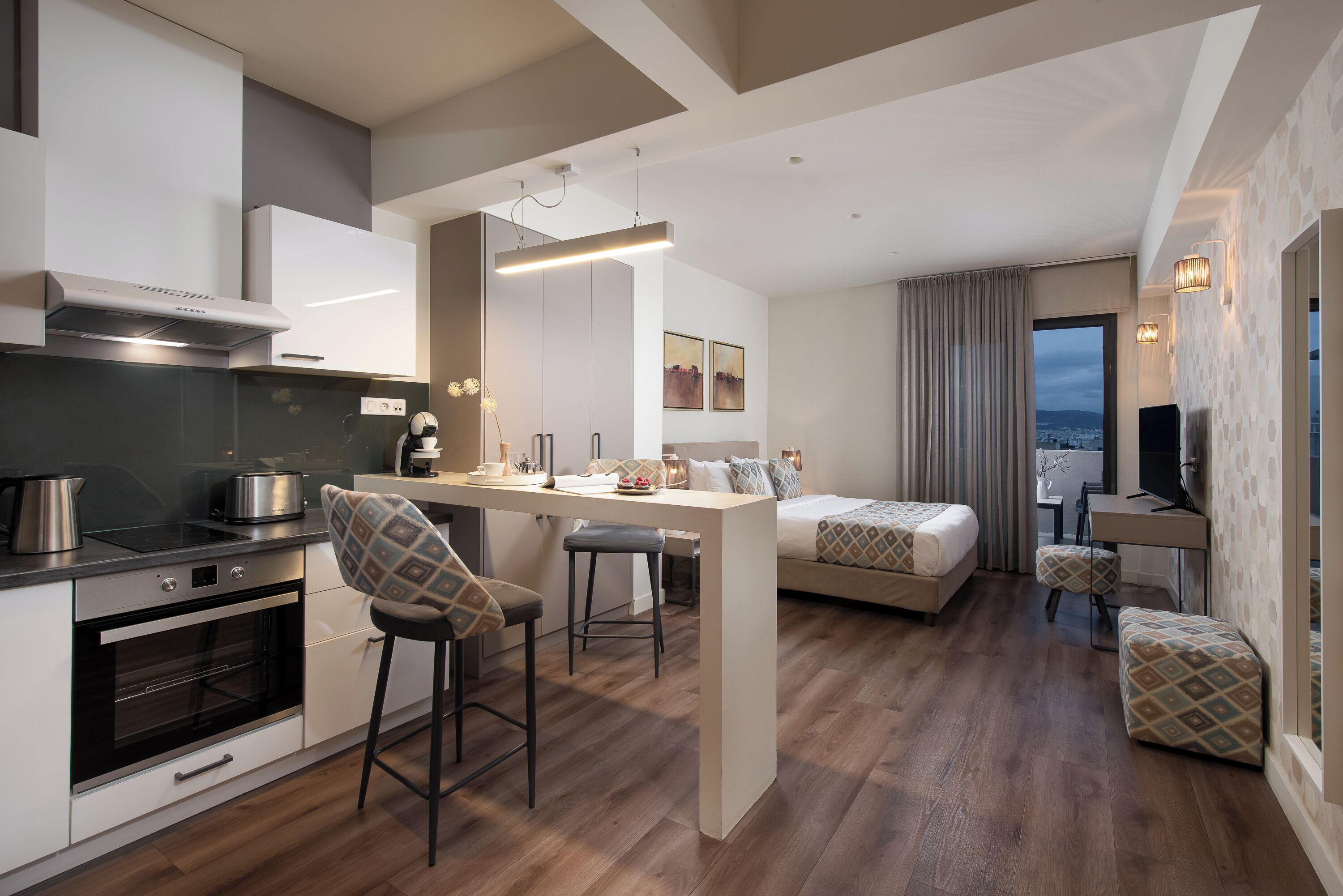 Una cocina moderna con una isla central, un comedor, un sofá y un televisor.