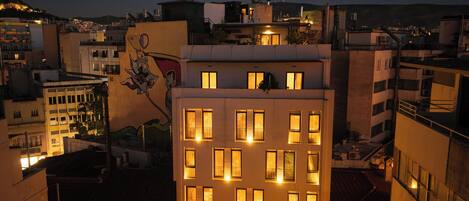 A multi-story building with illuminated windows and balconies, featuring a prominent mural on the side.