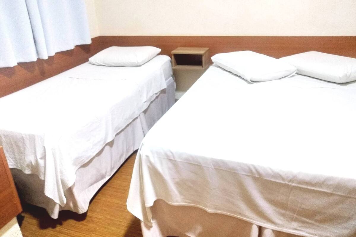 Una habitación con dos camas individuales, cada una con una almohada y una mesita de noche.