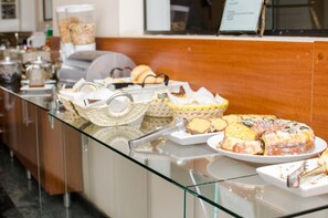 A buffet counter with various food items and utensils. - Lelis Hotel (Itapira)