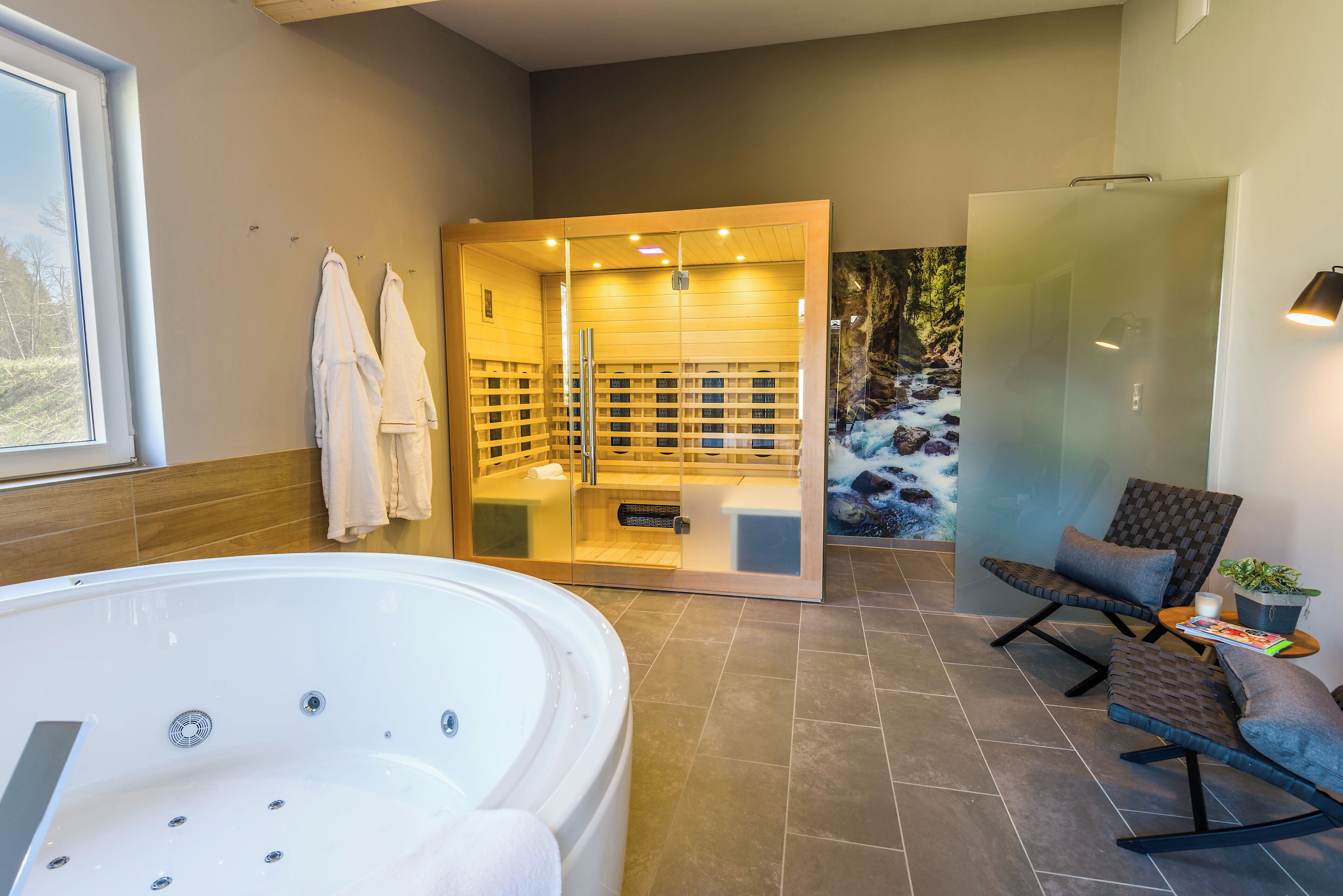 Ein modernes Badezimmer mit einer großen Badewanne, einer gläsernen Dusche und einer Sitzgelegenheit mit einem Blumentopf.