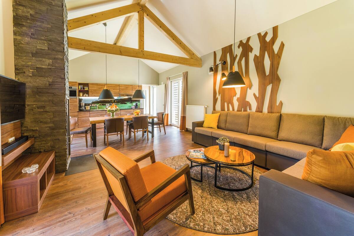 A spacious living area with a wooden ceiling, a sofa, a coffee table, and a TV.